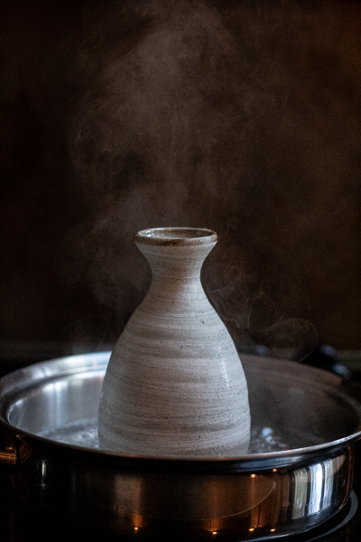 Heating carafe of sake on stove top